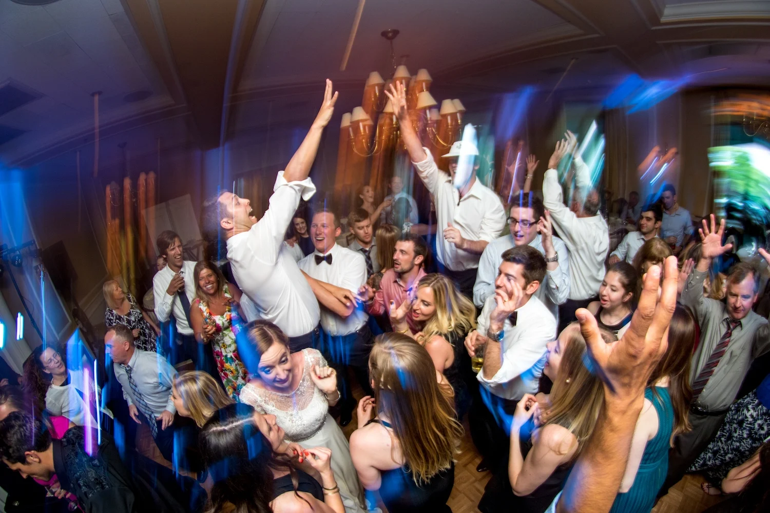 Wedding guests and the bride filling the dance floor with their hands in the air